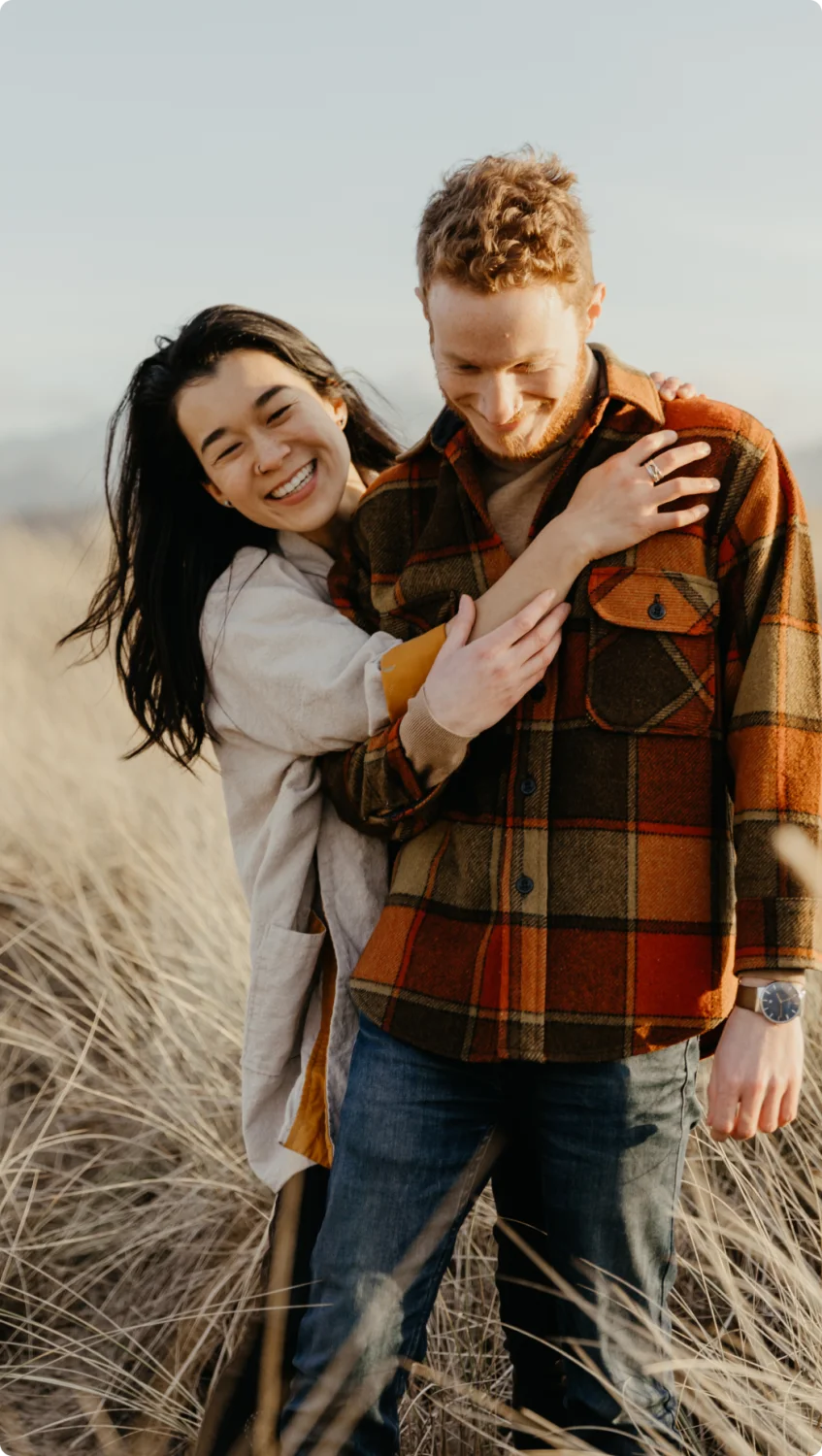 An asian woman and white man in a field enjoying a fall day