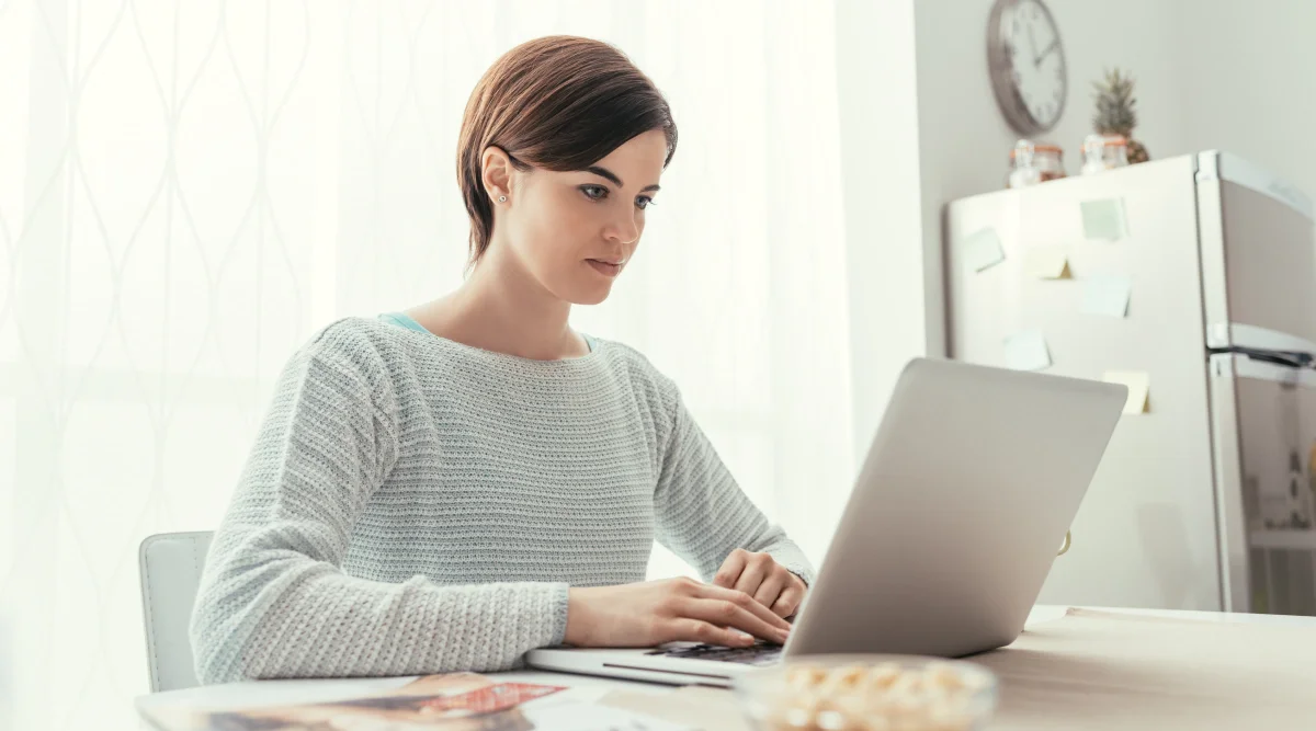 Woman in sweater working on laptop at home