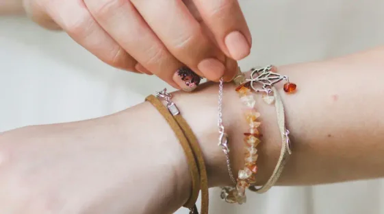 Close up of a hand clasping many bracelets on their other arm.