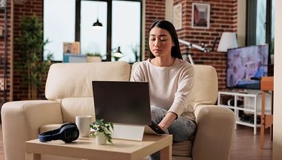 A professional woman sitting on her couch working on her computer