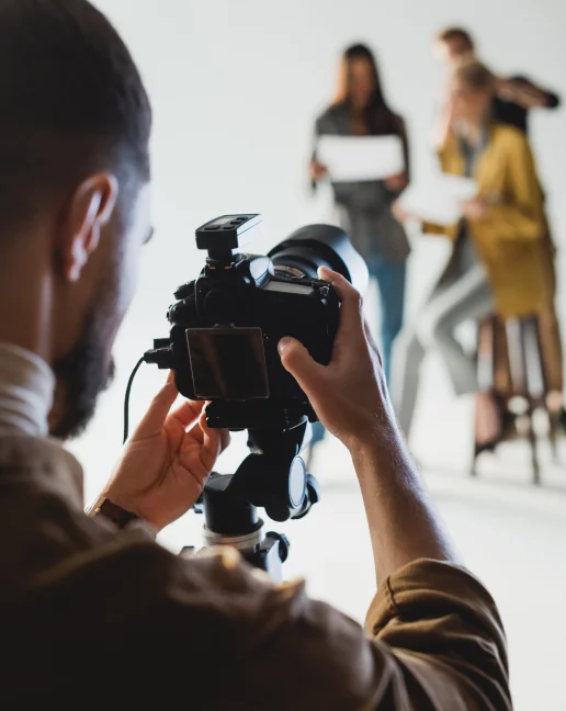 Man standing behind a professional camera setting up a photoshoot with two women after getting his business license though LegalZoom.