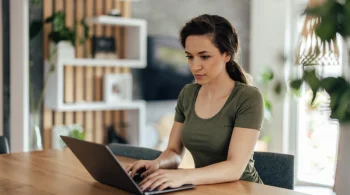 Woman in green shirt working on a laptop at home