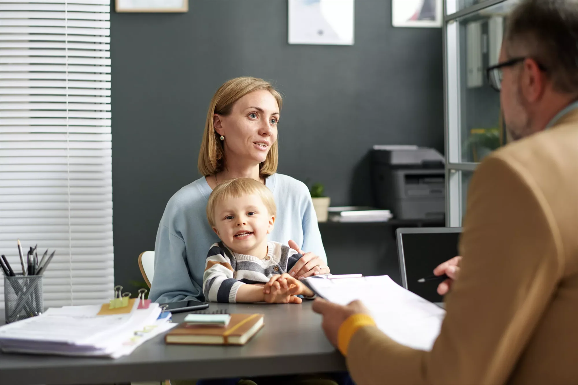 A woman with a child on her lap is talking to an attorney about trustee duties.