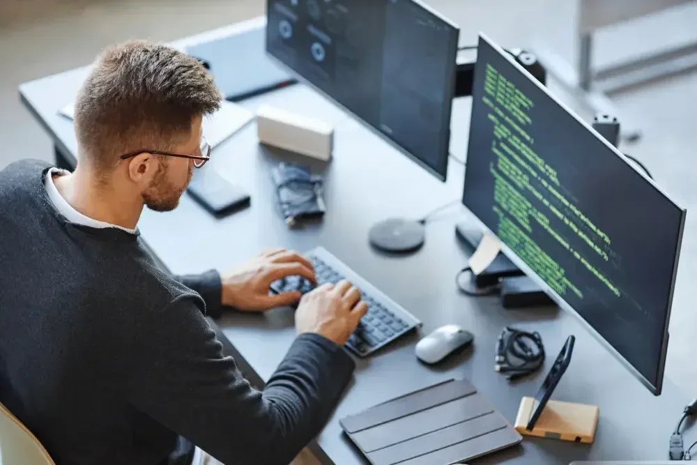 A freelance tech consultant writes code on his computer at his coworking space.