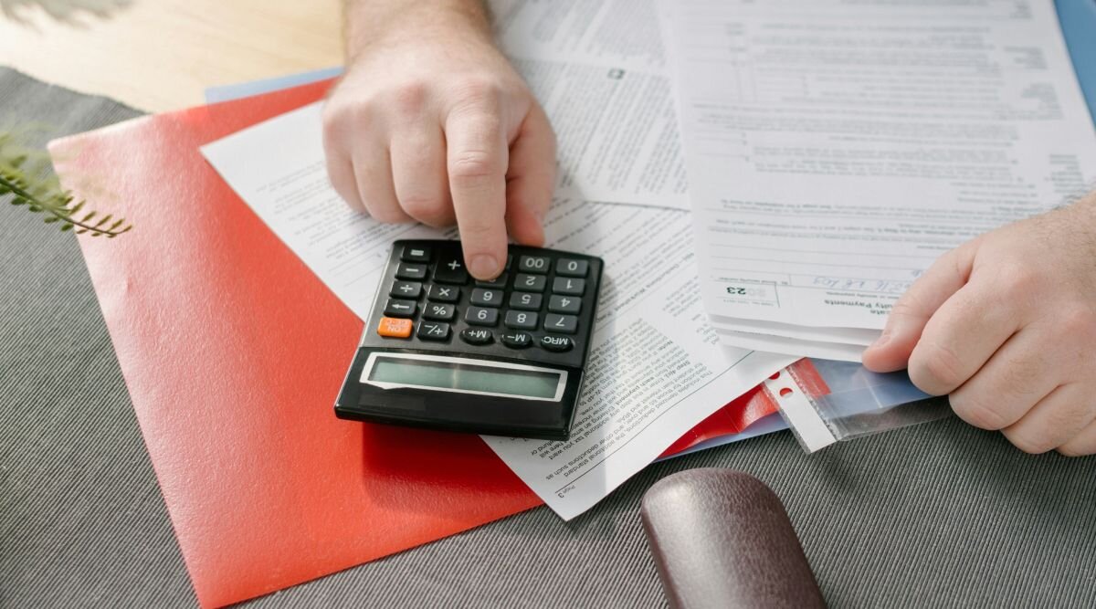 A corporation owner uses a calculator while filling out tax forms.