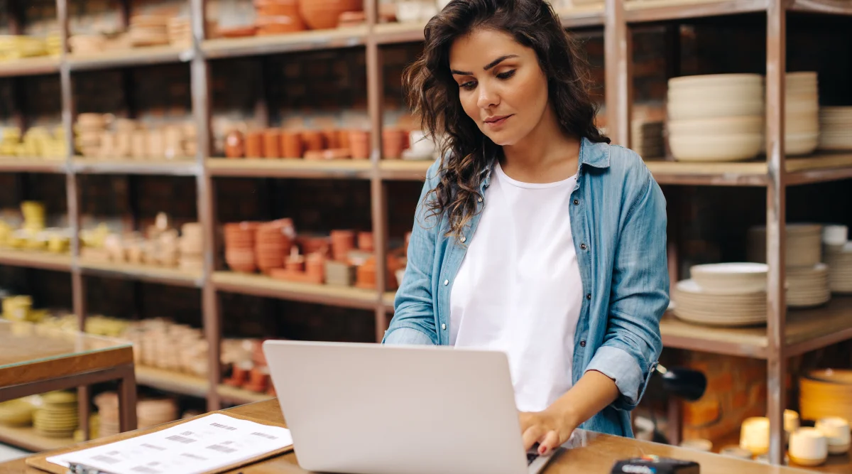 Woman looks over laptop in ceramic studio