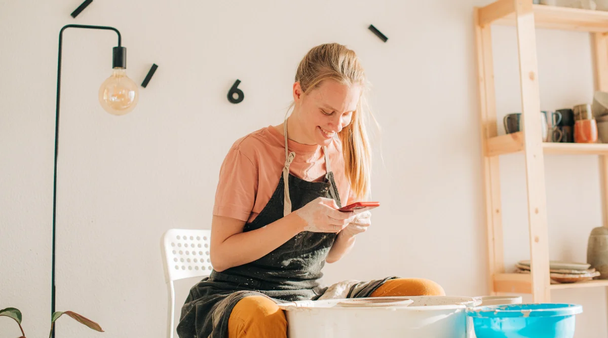 Woman using a phone during pottery making