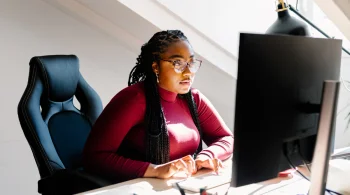 Woman focused on desktop computer in bright space