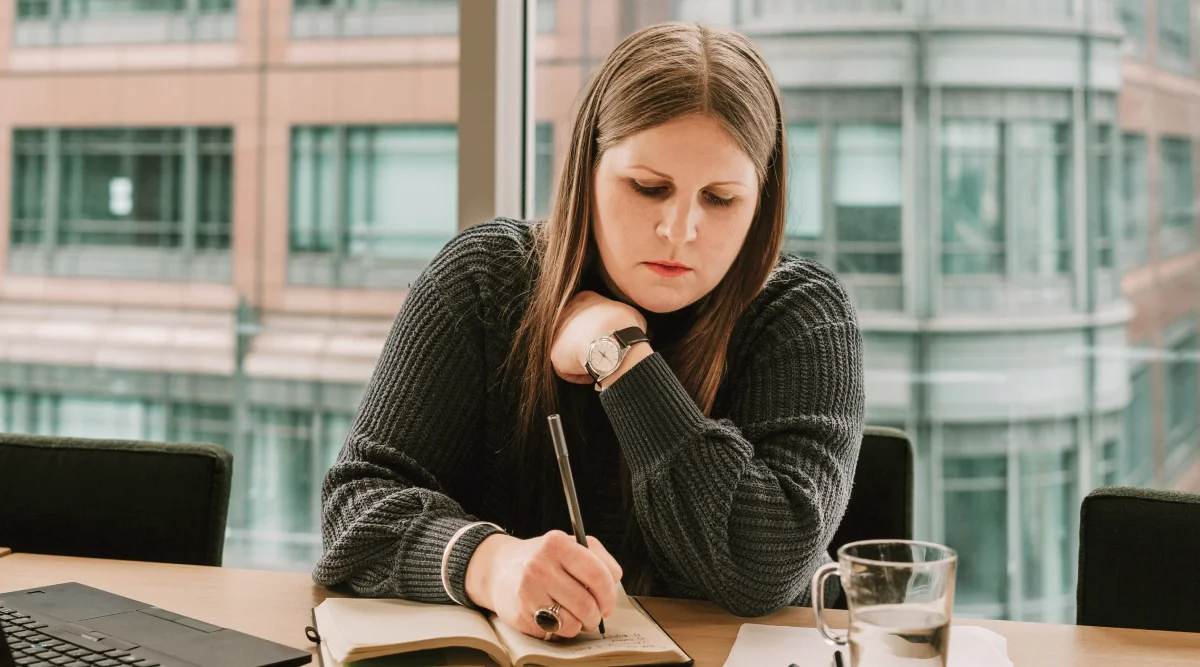 Woman writing in a notebook at an office desk