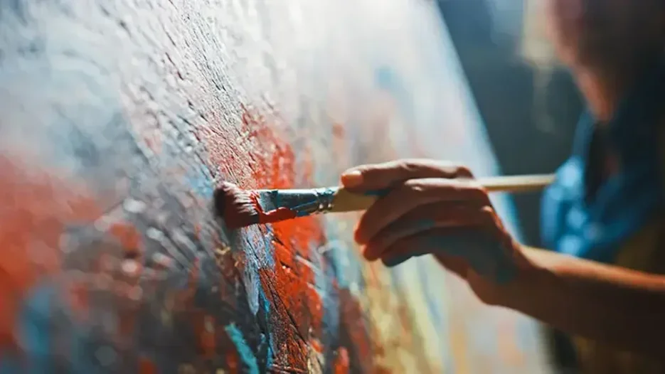 An artist paints on a canvas. Artwork can be designated to a beneficiary or beneficiaries in a trust. Creating a trust ensures that your assets will be handed off to your beneficiaries as per your wishes.