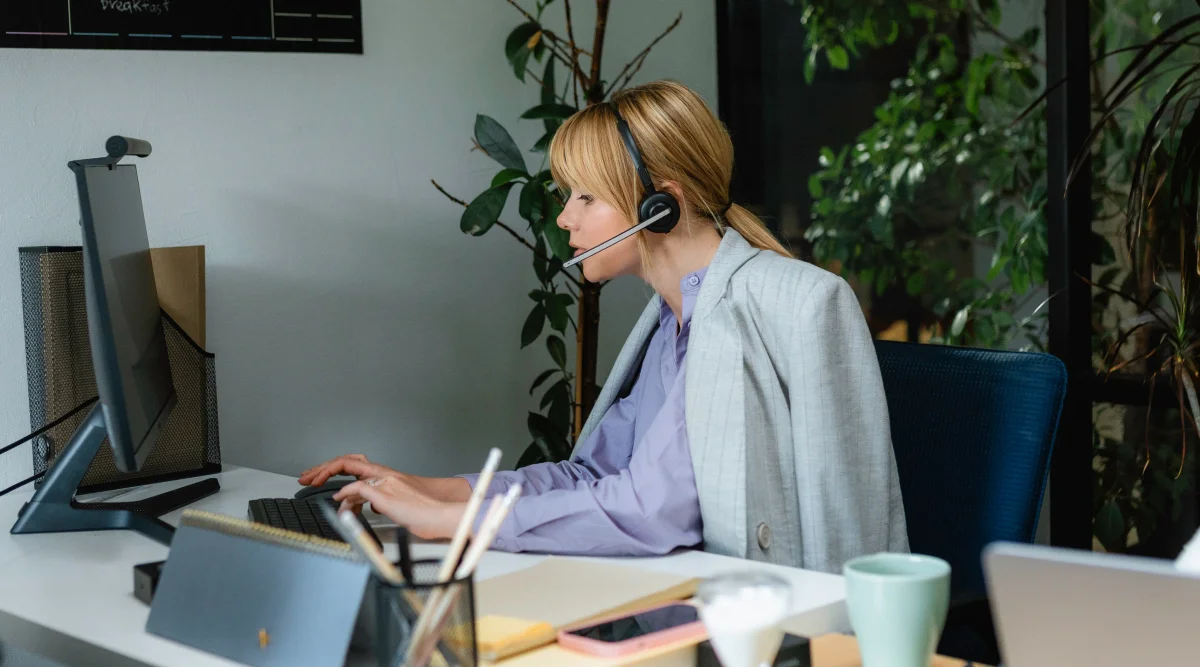 Woman with a headset working on a desktop computer