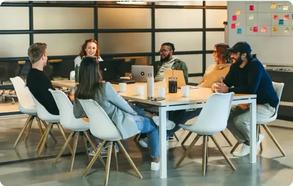 group of coworkers join at a large desk for a meeting