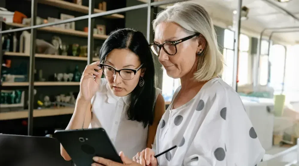 Two women business owners in South Dakota read a tablet for instructions on how to form an LLC there.