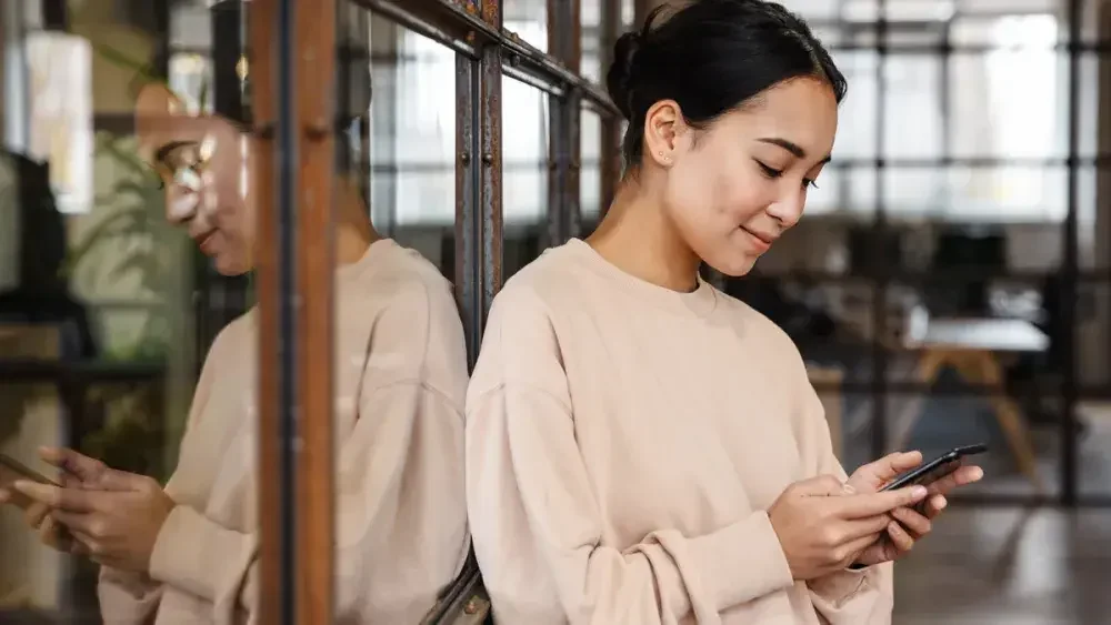 A young woman reads about estate planning on her phone. If you have a simple estate, you may be a good candidate to use a last will and testament template. 