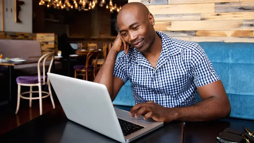 A man with an open laptop sits in a cafe and reads about forming an LLC in Illinois.