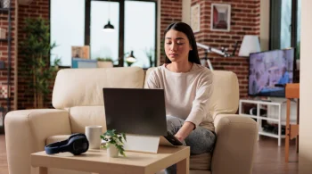 Woman using a laptop on a couch in a cozy room