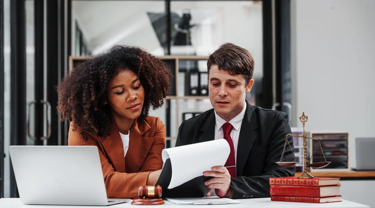 Man and woman look at a document in a modern office, trying to understand if they need a lawyer to start an LLC