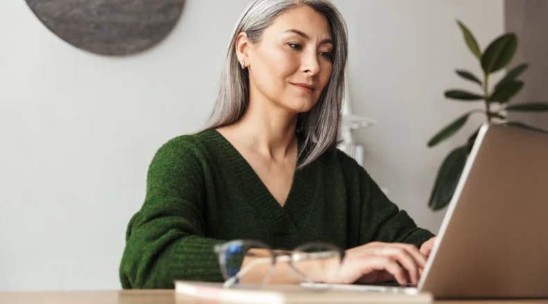 A woman stands behind the counter of her jewelry shop and writes in a notebook