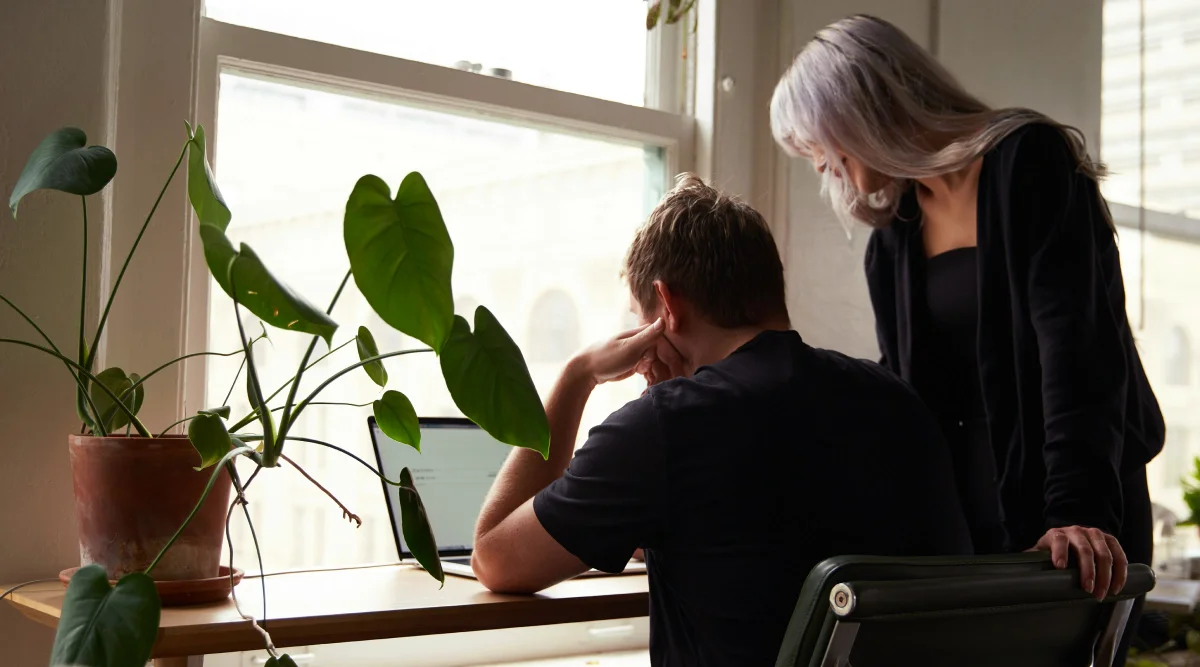 Two people looking at a laptop near a window