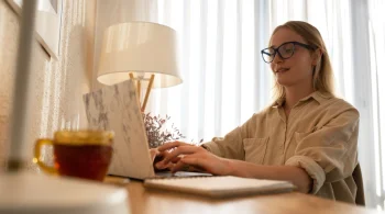 Woman typing on a laptop in a warmly lit room