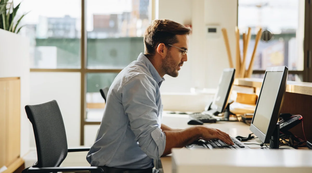 Man typing at a desktop computer in a modern office