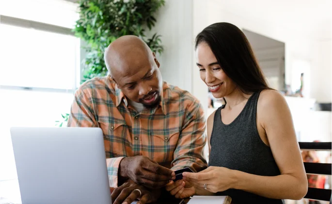 A man and woman browse their computer in their modern home.