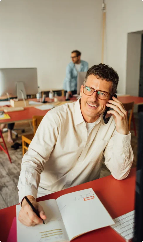 A man works and chats on the phone in a cafe