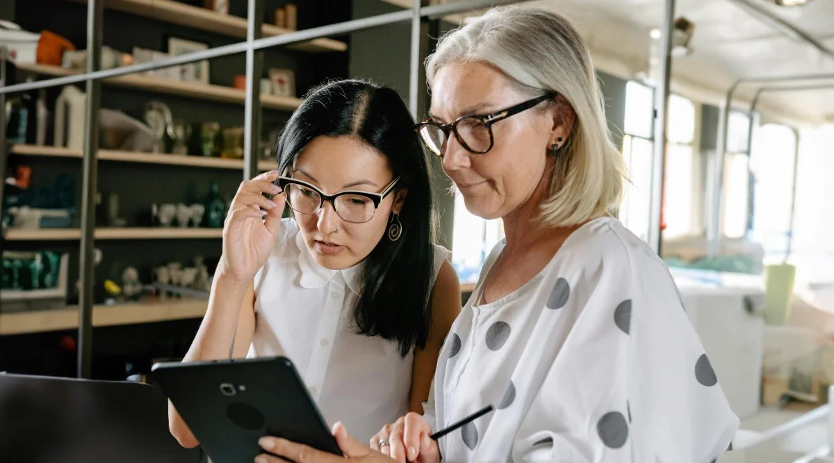 Two women collaborating on a tablet in an office