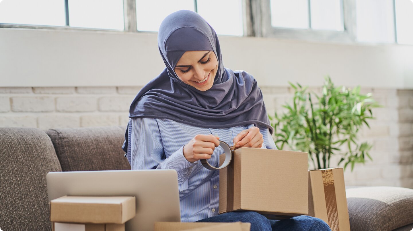 A woman wearing a hijab tapping a box closed.