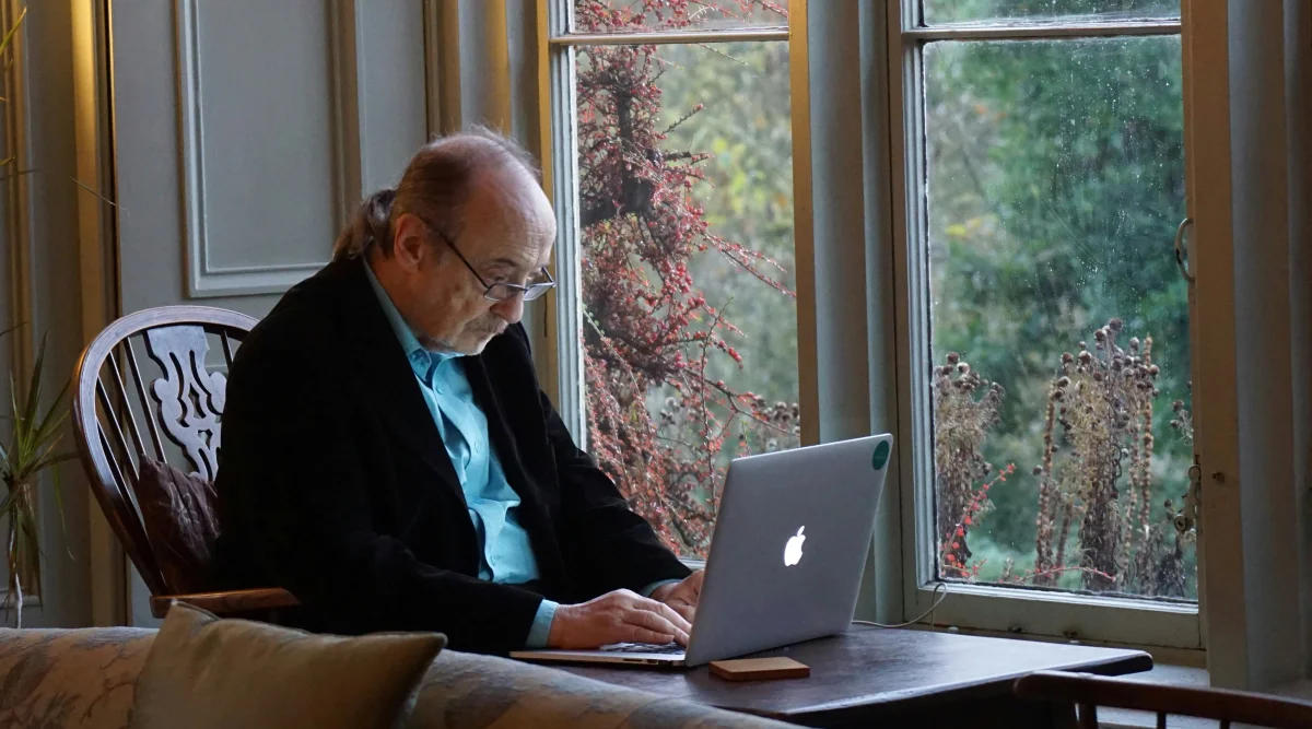 Man by window, working on laptop