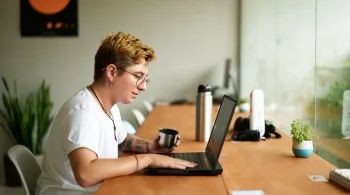 Person with coffee working on laptop