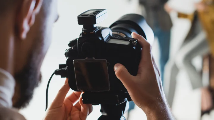 Man standing behind a professional camera setting up a photoshoot with two women after getting his business license though LegalZoom.