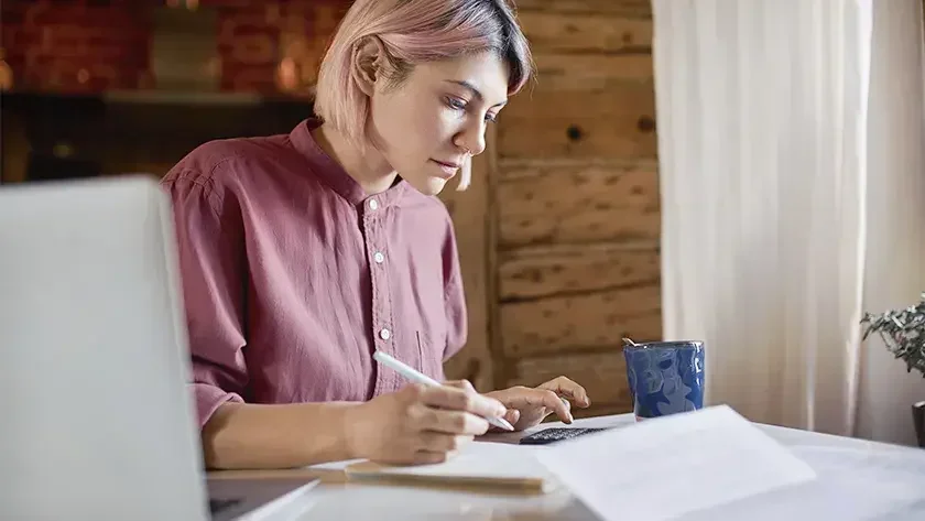 woman in pink shirt doing the books in her home office