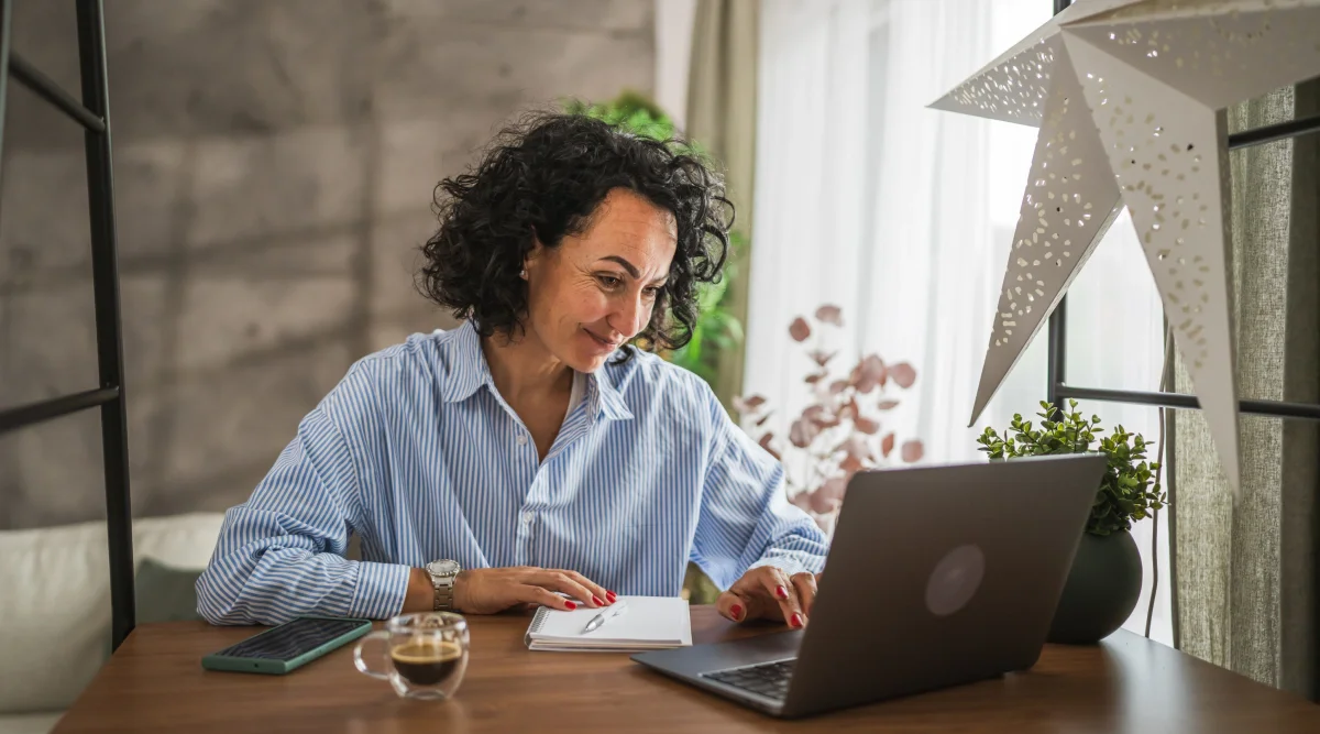 Woman writing notes with laptop and coffee