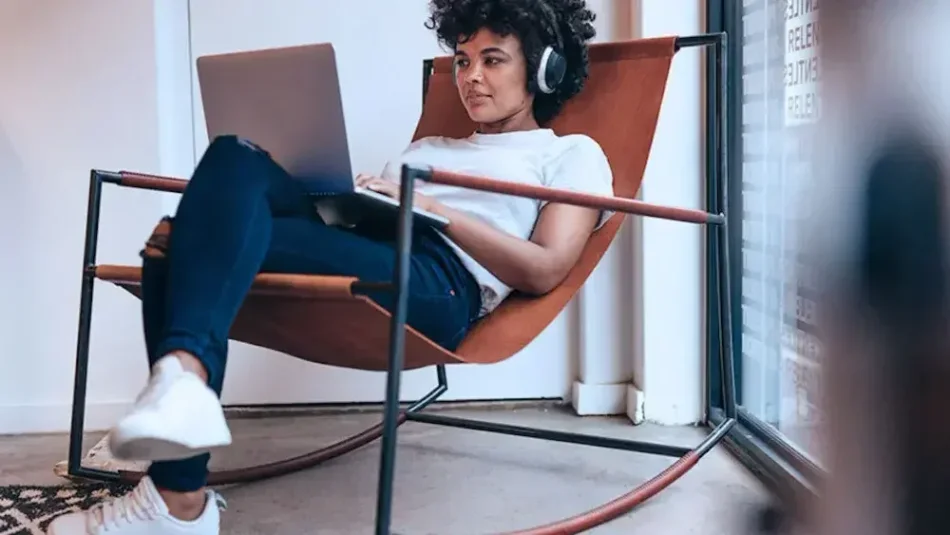 A woman wearing headphones sits in a chair and reads onscreen about forming an LLC in New York.