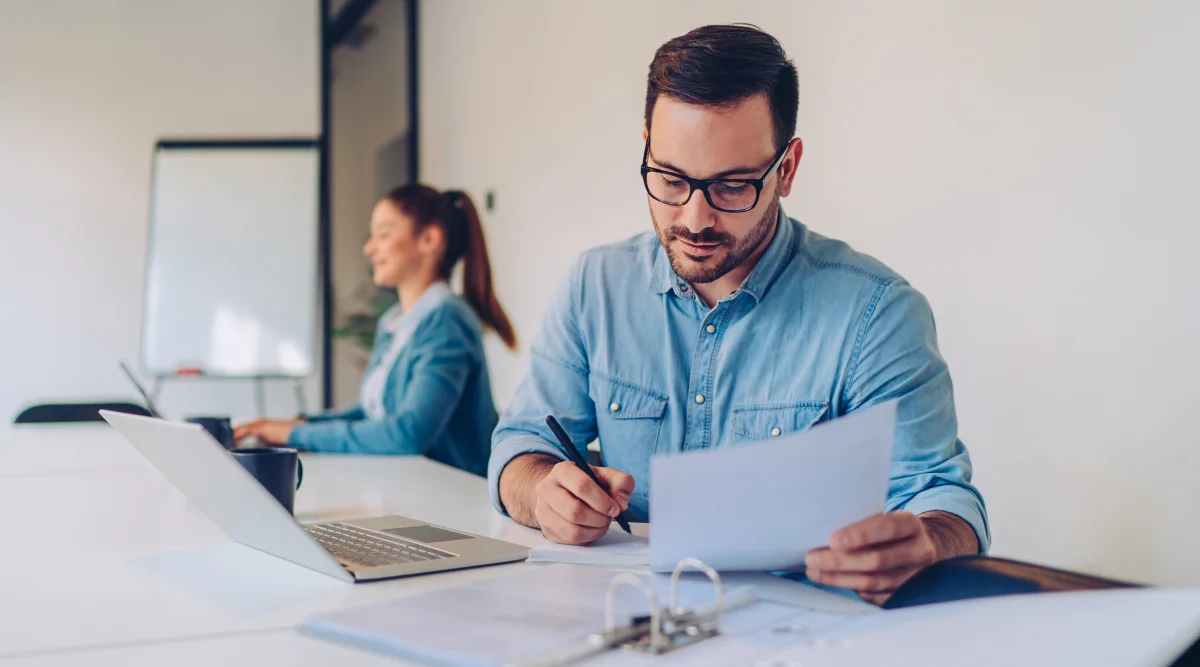 Man in glasses reviewing a document at a desk