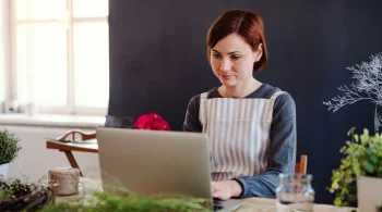 Woman in apron using laptop in a cozy room