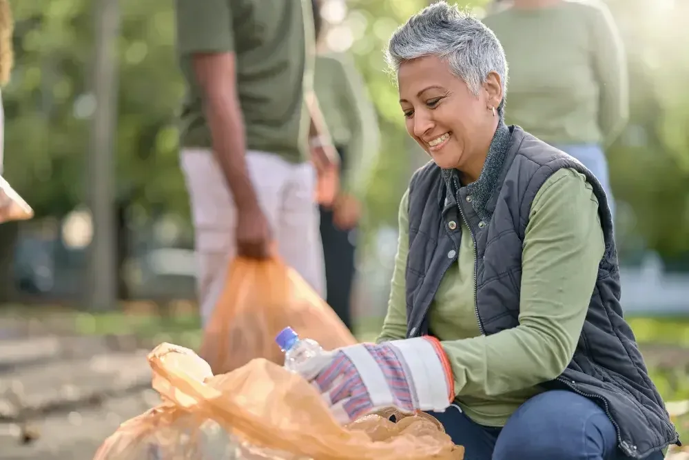 The leader of a nonprofit helps her team pick up recyclables in a public park.