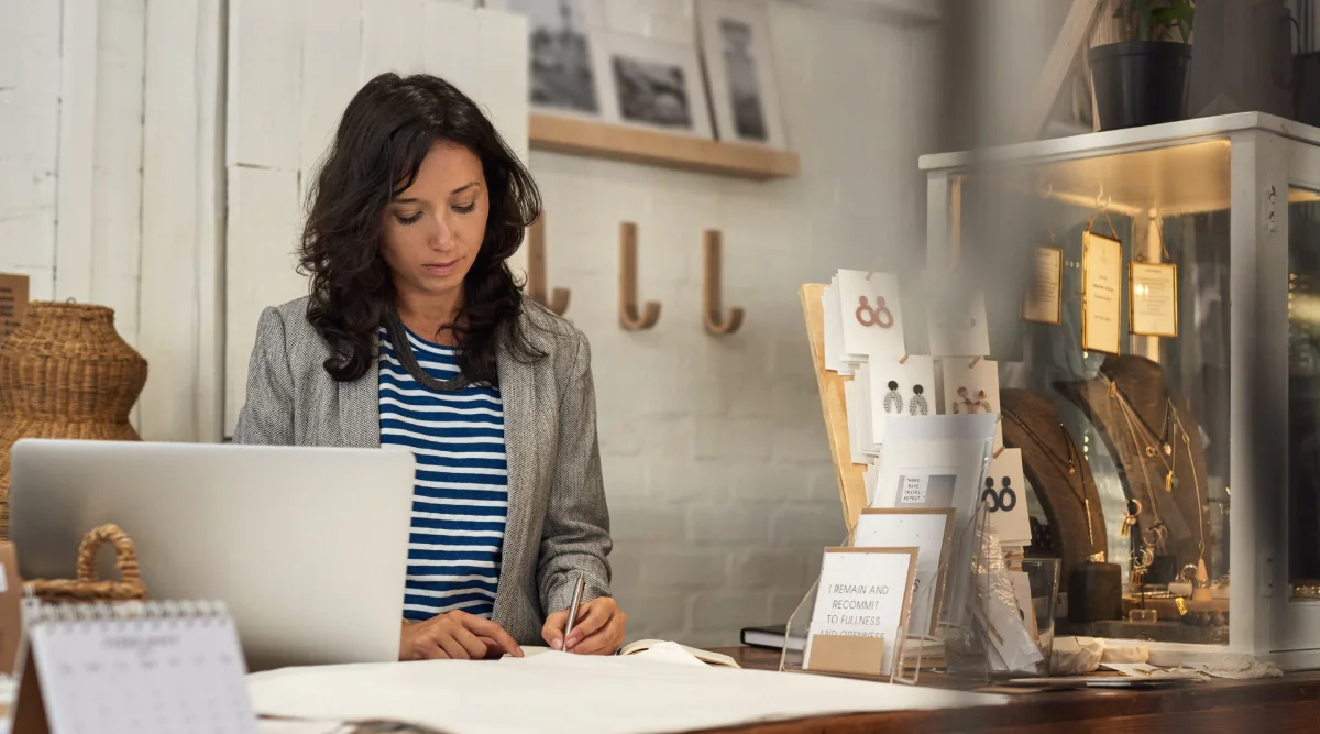 Woman working at a desk in a boutique with a laptop