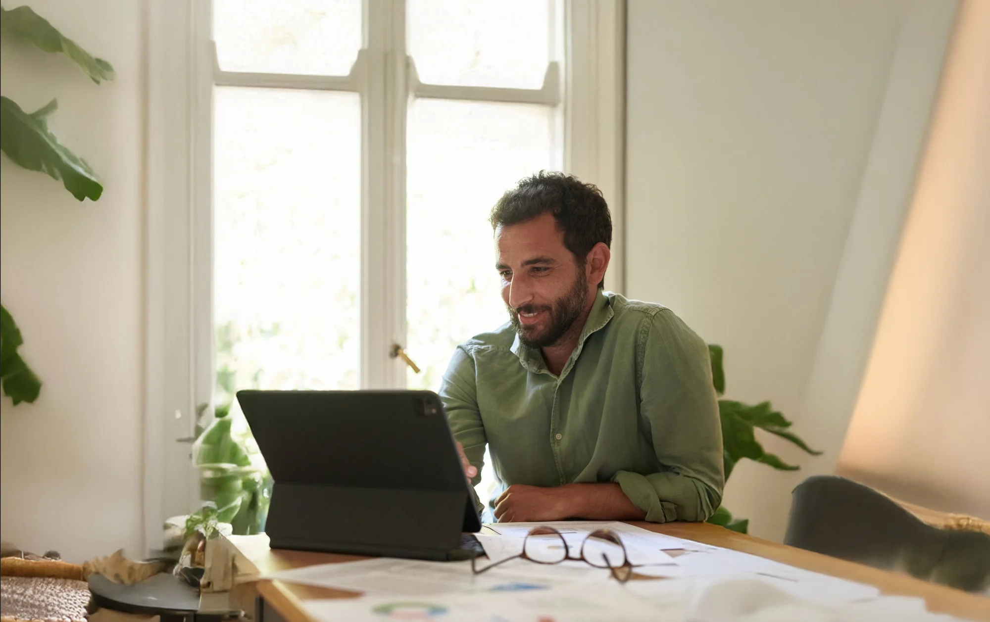 A man sits at a desk using a tablet