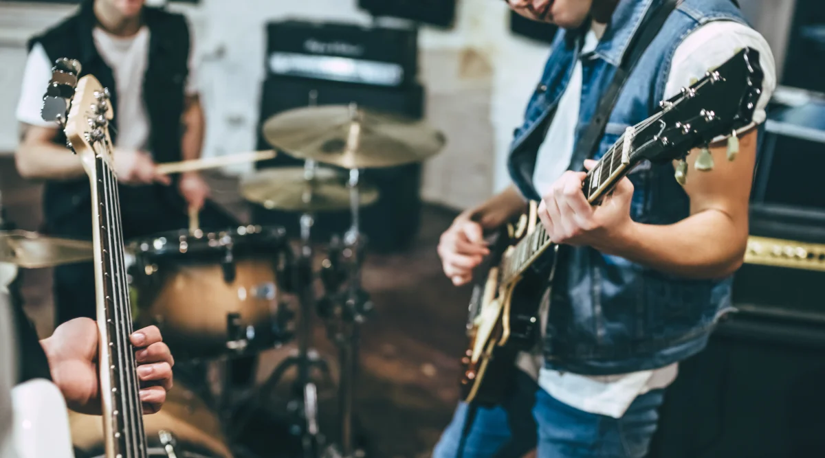 A band practices and while they play their instruments they wonder about how to trademark a band name.