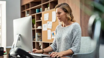 Woman using a desktop in an organized office setting.