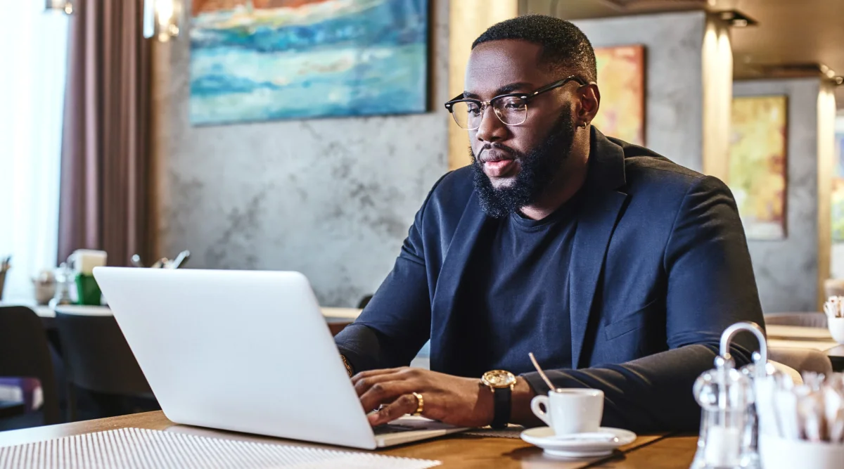 Man in glasses working on laptop in a cafe