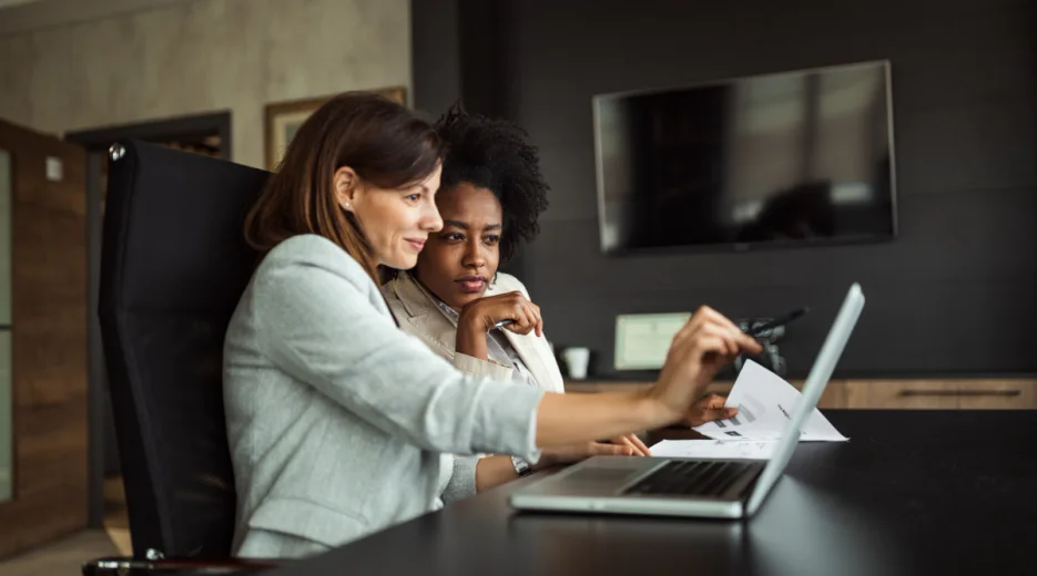 An image of two women in a conference room, discussing state-specific spendthrift trust rules.