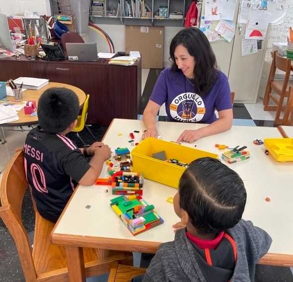 A school counselor is meeting with two young children while they play with Legos.