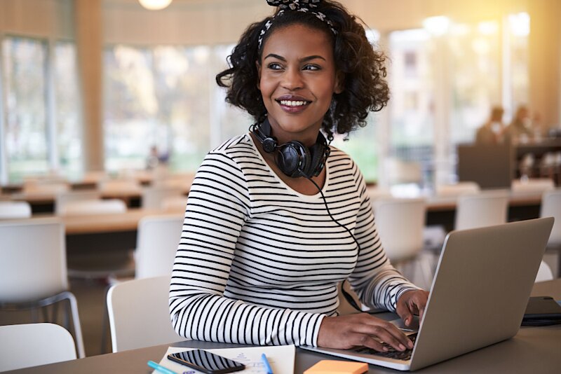 A woman is in a classroom working on her laptop. 
