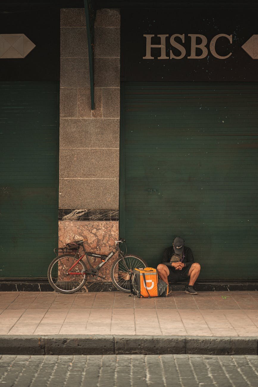 man looking at ground with back against the wall