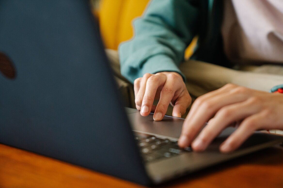 Close-up of hands typing on a laptop at a wooden desk while using tax software