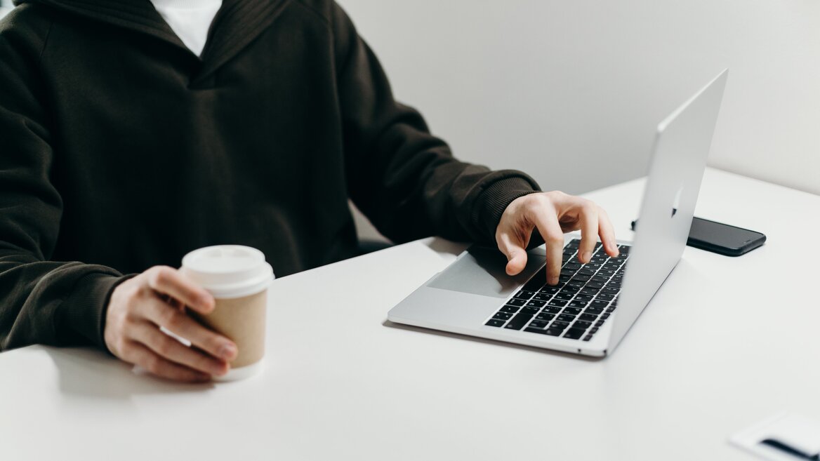 A contractor working on a laptop with a coffee cup, representing a calm and organised approach to finances
