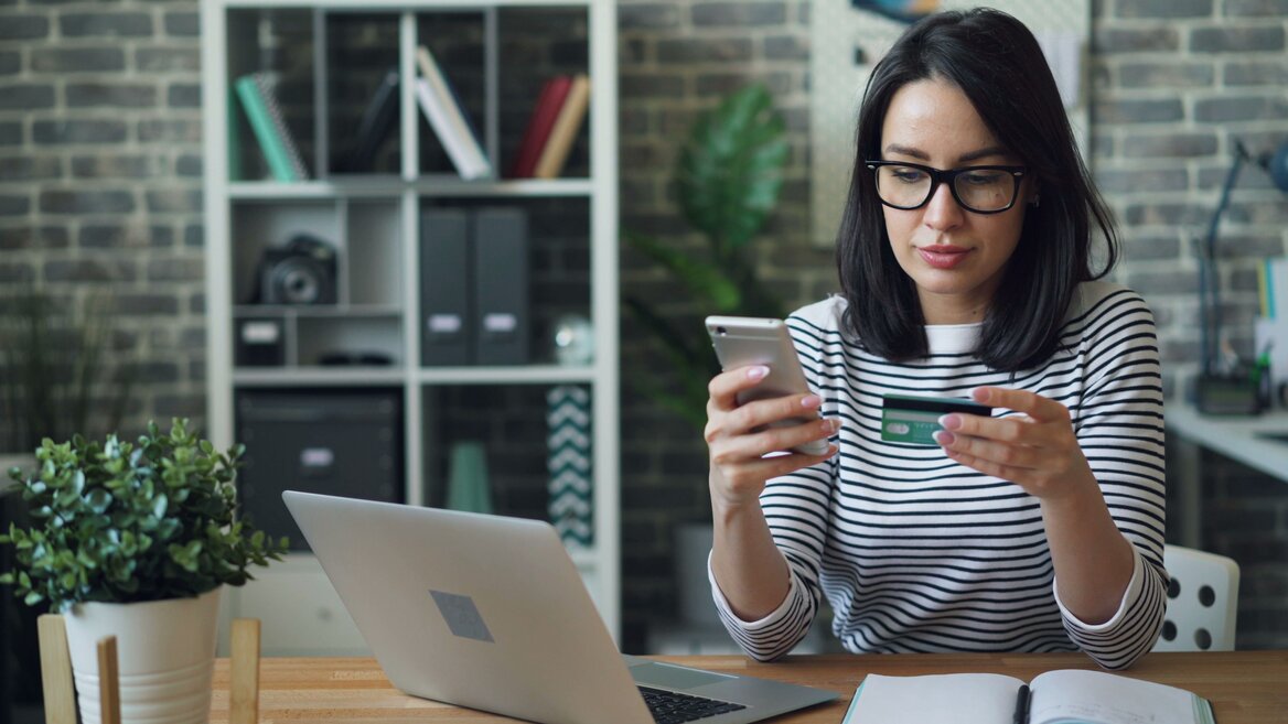 Person holding a debit card while managing their bank account online